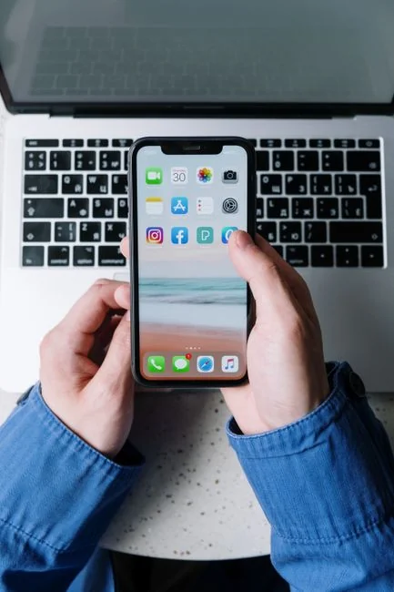 Un espace de travail contemporain où des mains examinent des données marketing sur un ordinateur portable et des documents papier.